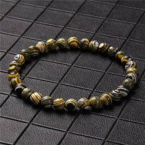 Close-up of a 6mm yellow and black malachite stone beaded bracelet on black grid