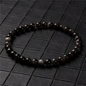 Detailed close-up of a 6mm black cat's eye stone beaded bracelet on grid background