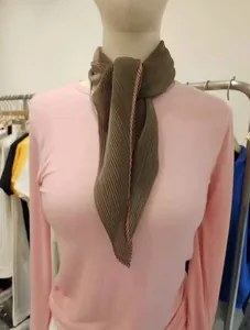 Gedetailleerde opname van een bruine geplooide sjaal gestyled op een roze t-shirt