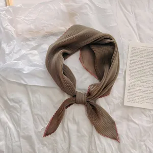 Detailopname van een elegante kaki geplooide zijden sjaal op een fris wit laken