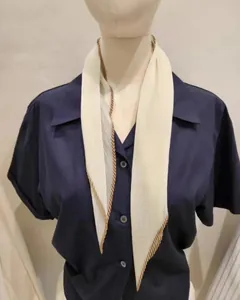 Detail van een elegante crème geplooide zijden sjaal gedragen over een donkerblauw shirt