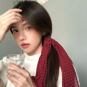 Elegante foulard in seta bordeaux a pois annodato sulla coda per un affascinante look retrò