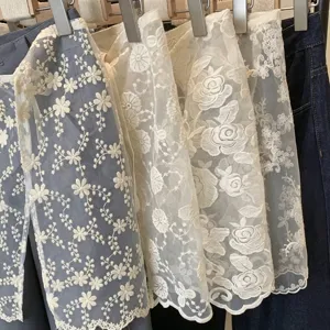 Primo piano del ricamo floreale su gonna in organza bianca leggera e trasparente.
