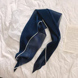 Detailopname van een marineblauwe geplooide sjaal met witte contrastranden
