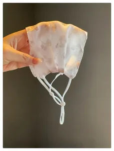 Vue détaillée d'un masque de protection solaire en maille fleurie avec boucles.