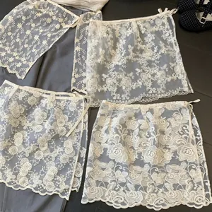 Collezione di grembiuli in pizzo e organza bianchi con vari ricami floreali