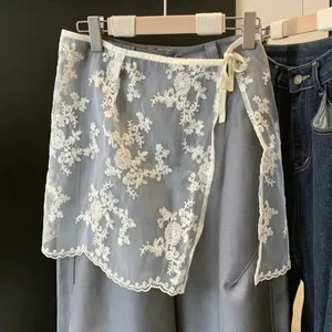Dettaglio della gonna sovrapposta in pizzo di organza con ricami floreali bianchi.