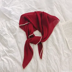 Elegante geplooide rode halsdoek met witte golvende randen op witte stof