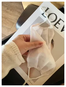 Gros plan détaillé du masque facial en mesh blanc respirant avec imprimé floral subtil chic