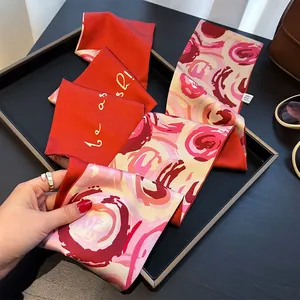 Écharpe longue et étroite en soie à motif floral rouge et rose sur un plateau noir