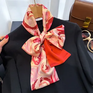 Élégante écharpe étroite en imitation soie fleurie nouée sur un pull noir sophistiqué