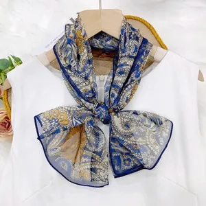 Detailed view of an ornamental paisley print thin ribbon scarf tied in a bow over white top