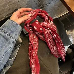 Dettaglio di un foulard vintage in seta rossa con motivo paisley usato come nastro per capelli