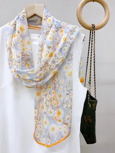 Detailed view of sheer floral scarf featuring yellow daisy prints and elegant orange trim
