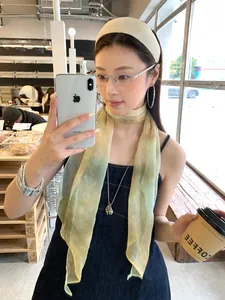 Dettaglio di un fresco foulard in seta sfumata giallo-verde indossato come cravatta