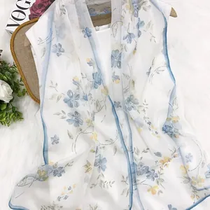 Close-up detail of a white georgette floral scarf with elegant blue and yellow patterns