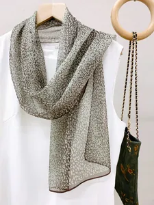 Detailed view of lightweight leopard print gauze scarf draped on a white top
