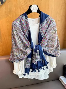 Detailed view of a navy blue ethnic print scarf with tassels on a white casual top.