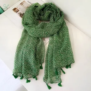 Close-up of lightweight green floral scarf with decorative fringe tassels on edges.
