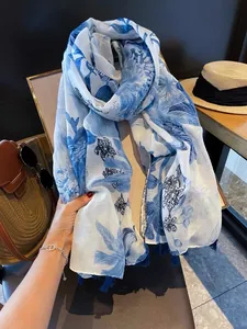 Detailed close-up view of a thin summer floral silk scarf featuring elegant blue tassels and pattern