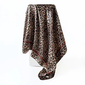 Close-up detail of leopard print satin square scarf showing smooth texture and elegant drape
