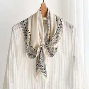 Elegant vintage cream silk scarf with black paisley print tied on a minimalist white shirt