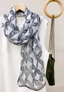Detail view of a thin chiffon scarf with a black chain link pattern on a hanger