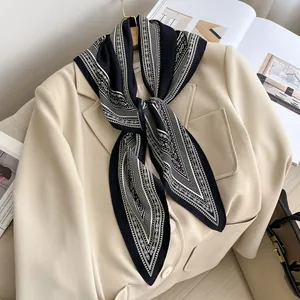 Elegant detail of a retro black paisley silk scarf styled on a chic beige blazer