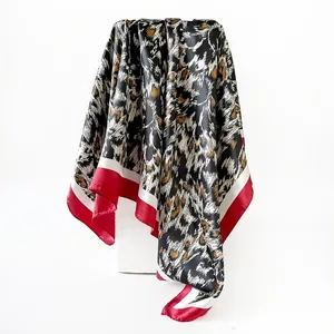 Detailed macro view of leopard print satin square scarf with vibrant red border trim