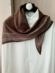 Detailed view of the brown retro silk scarf with a paisley pattern border draped on a shirt