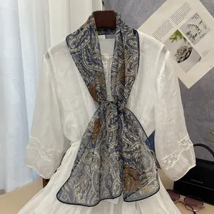 Elegant blue and brown paisley pattern sheer long scarf for women draped on a white dress