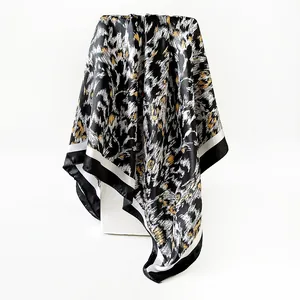Detail view of a leopard print satin square scarf draped on a white pedestal