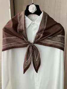 Macro view of a vintage brown paisley silk scarf elegantly draped over a white shirt