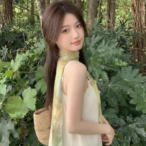Sciarpa sottile a fantasia gialla e verde indossata da una modella in una foresta lussureggiante