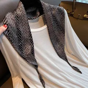 Close-up of black and white herringbone pattern triangular silk scarf styled on white shirt