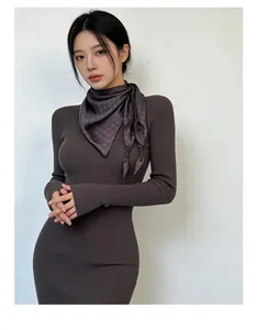 Detailed view of an elegant plaid silk scarf paired with a brown ribbed dress on a model.