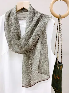 Detail view of a long animal print silk scarf draped over a white dress for styling.