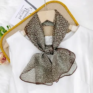 Detailed view of a tied leopard print chiffon scarf on a white blouse hanger.