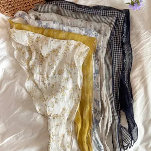 Close-up of various vintage patterned linen triangular head scarves on white fabric