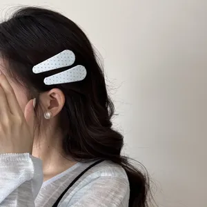 Detailweergave van schattige witte stoffen haarspelden met stippen in het haar