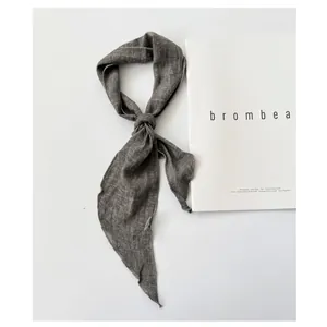 Close-up of a knotted gray-green ramie neck scarf displayed on a white magazine