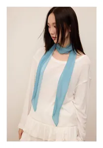 Close-up of light blue pleated long ribbon scarf worn as a stylish neck tie.