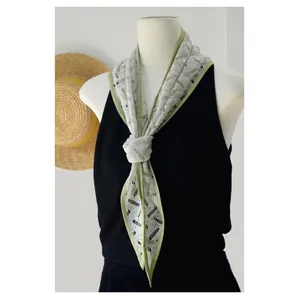 Dettaglio di un foulard a triangolo in pizzo floreale verde menta su un manichino