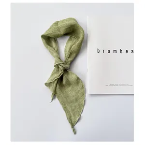 Close-up detail of a light green ramie scarf showing the natural knotted linen texture