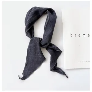 Close-up detail showing the texture of charcoal grey ramie linen skinny scarf knotted on white
