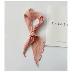 Macro detail of a pink minimalist ramie skinny scarf tied in a loose stylish knot