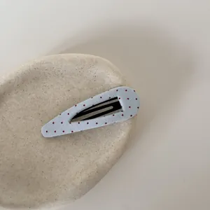 Detailopname van een schattige blauwe en rode polkadot stoffen haarklem op stenen blad