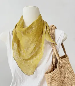 Primo piano di un foulard triangolare in puro lino giallo senape drappeggiato su un manichino