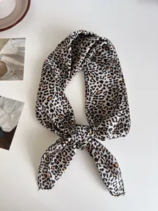 Dettaglio di un foulard di seta con stampa leopardata annodato con stile