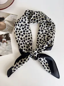 Primo piano di un elegante foulard quadrato in raso a pois bianchi e neri con nodo